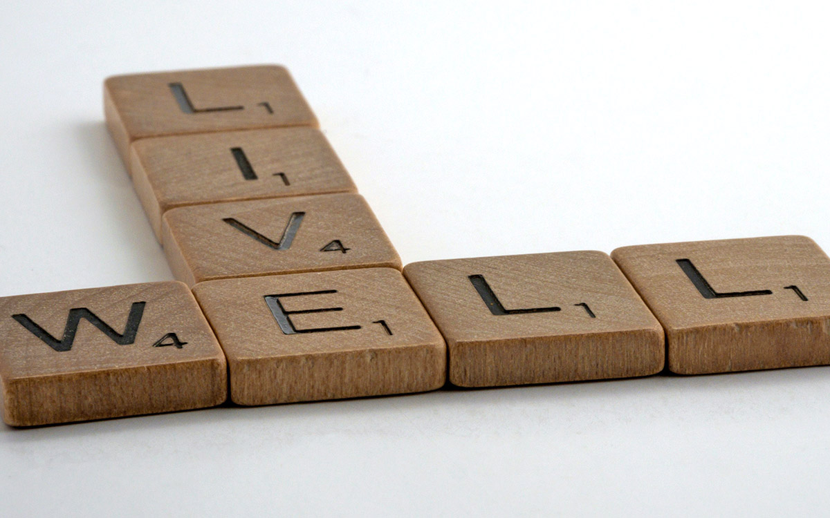 Wooden letter tiles spelling out words 'live' and 'well'