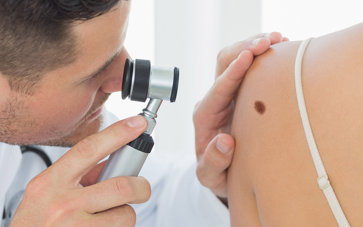 Doctor making a close examination of a skin blemish on a woman's shoulder